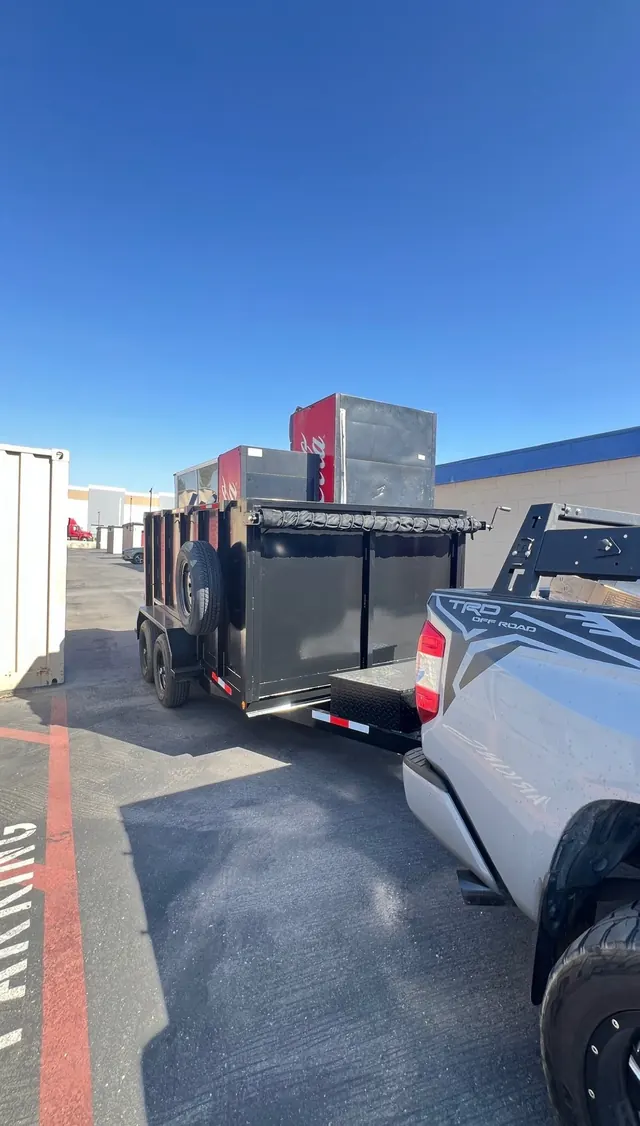 Dump trailer loaded high with metal appliances and cabinets in a parking lot