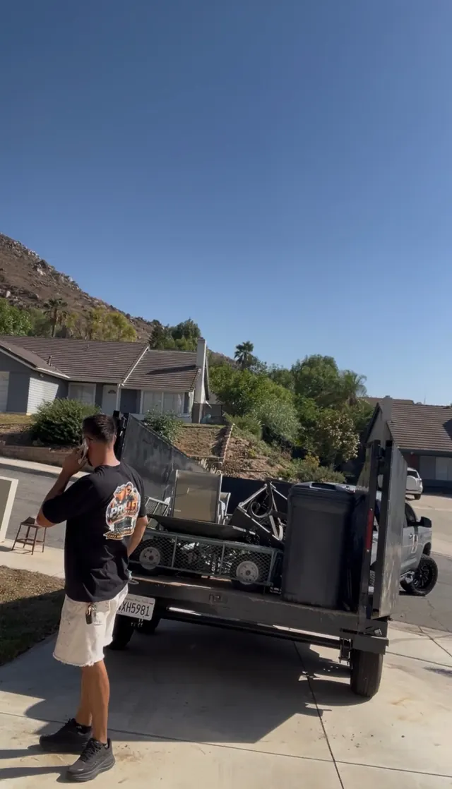 Crew member on the phone next to a loaded trailer outside a house